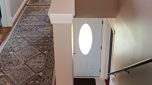 Eine Treppe mit weißer Handlauf, einem gemusterten Teppich und einer Tür mit rundem Fenster.