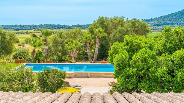 Una piscina con vista su un paesaggio collinare, circondata da verde e alberi.