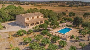 Una villa con piscina, immersa tra alberi e campi aperti.