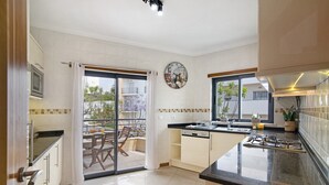 A modern kitchen with a large island, a microwave, and a gas stove. - Apartment with Marina and Sea Views – Shared Pool & Wi-Fi (Albufeira)