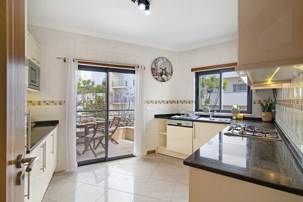 A modern kitchen with a large island, a microwave, and a gas stove.