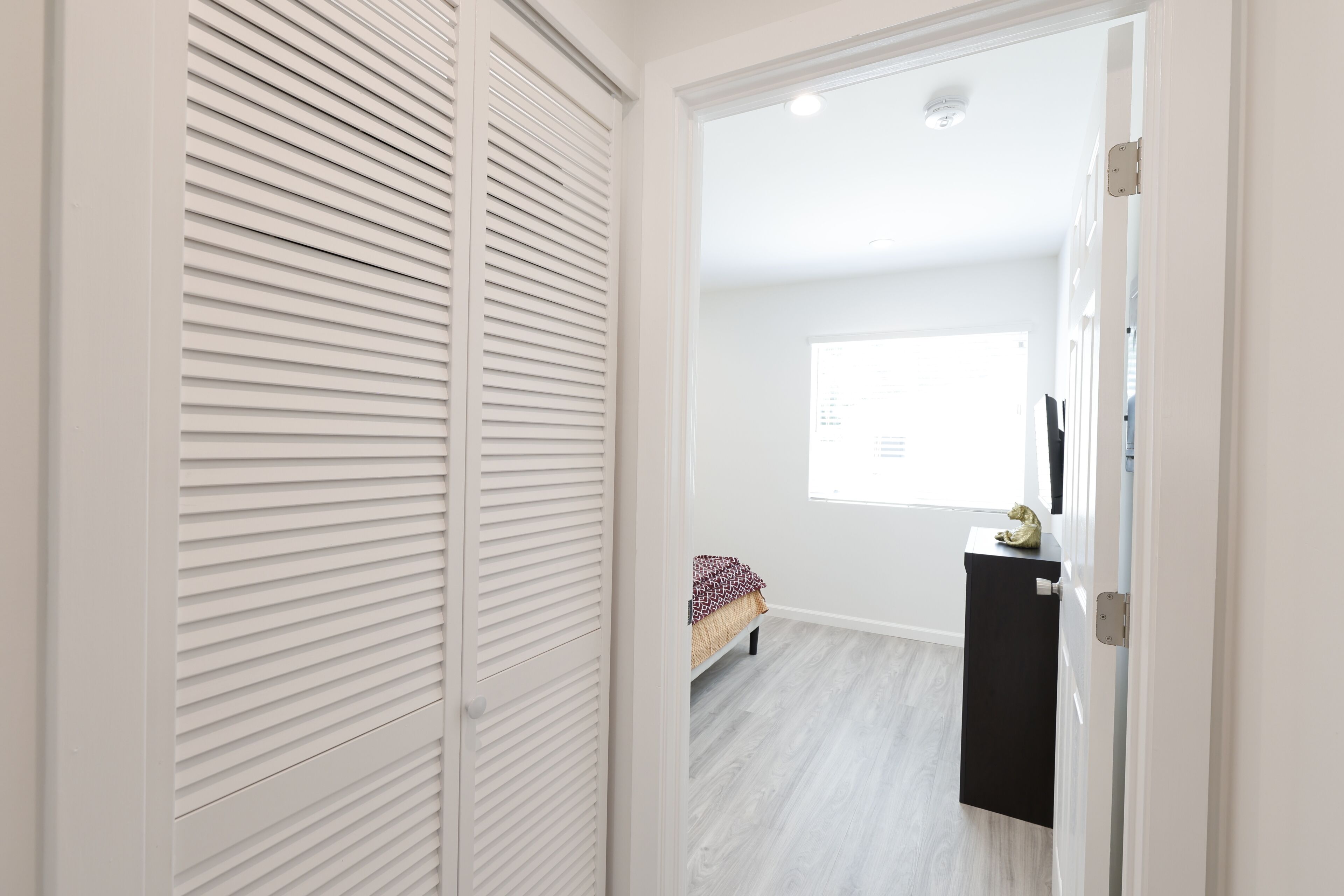 A room with a bed, a window, and a white door.