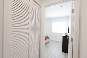 Une piĂšce avec un lit, une fenĂȘtre et une porte blanche.