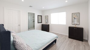Ein Schlafzimmer mit Bett, Tür, Fenster und Schrank.