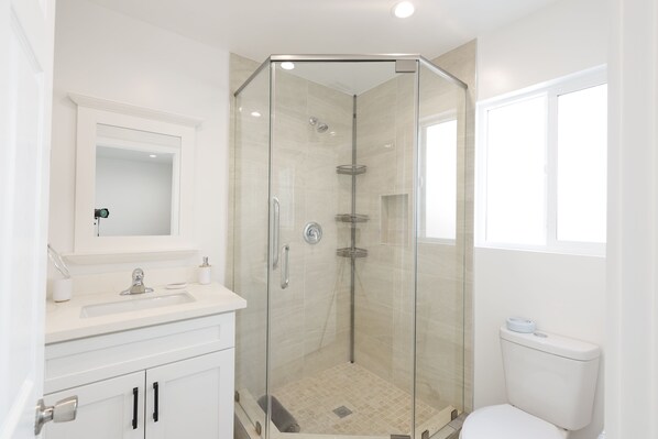 Une salle de bain moderne avec une douche Ă parois de verre, un lavabo blanc et des toilettes.