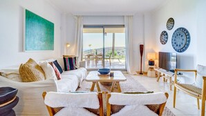 A spacious living room with a sofa, coffee table, and chairs, a TV, and decorative plates on the wall. - Apartment "Hacienda Senorio Cifuentes" with Sea View, Shared Pool & Wi-Fi (Benahavis)