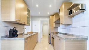 A modern kitchen with wooden cabinets, granite countertops, and stainless steel appliances. - Apartment "Hacienda Senorio Cifuentes" with Sea View, Shared Pool & Wi-Fi (Benahavis)