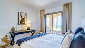 A hotel room with a bed, a desk with a lamp, a chair, and a view of the outdoors. - Apartment "Hacienda Senorio Cifuentes" with Sea View, Shared Pool & Wi-Fi (Benahavis)