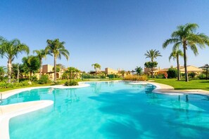 Una piscina azul cristalina rodeada de palmeras y edificios.