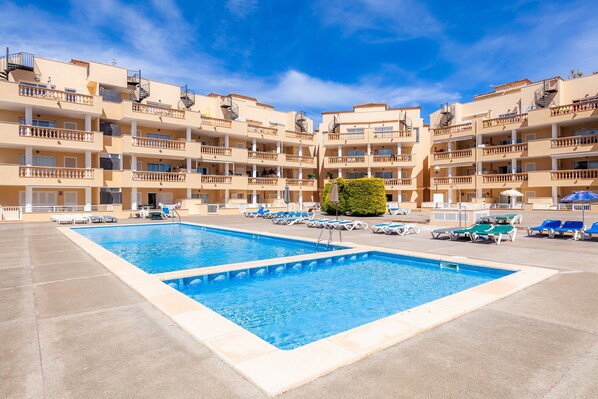 A hotel with multiple balconies, a swimming pool, and sun loungers. - Apartment 'Apartamento Espiga' with Shared Pool, Wi-Fi and Air Conditioning (Cala Bona)