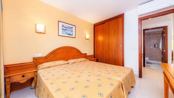A hotel room with a wooden bed, bedside tables, a wall-mounted picture, and a door leading to a bathroom.