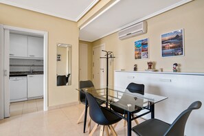 Une cuisine moderne avec des meubles blancs, un lave-vaisselle et une table à manger en verre, assortie de chaises noires.