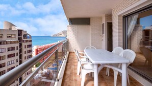 Ein Balkon mit Tisch und Stühlen mit Blick auf die Küste.