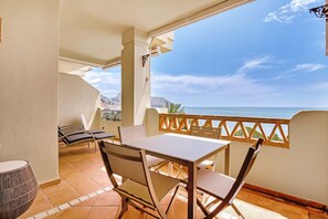 Un balcón con mesa y sillas, con vistas a la costa.