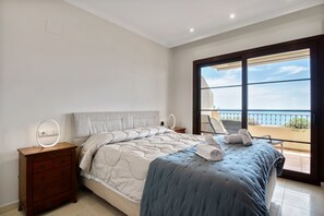 Un dormitorio con cama, mesita de noche, espejo y vistas al exterior.