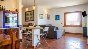 A kitchen with a stove, oven, and dining area with chairs and a table. - Villa "Glicine - Colleberto" with Sea View, Private Terrace & Wi-Fi (Follonica)