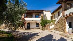 A courtyard with a building featuring a stone facade, arched doorways, and a balcony with potted plants. - Villa "Glicine - Colleberto" with Sea View, Private Terrace & Wi-Fi (Follonica)