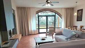 A living room with a sofa, armchair, dining table, and a fireplace. - Villa "Bouganville - Colleberto" with Sea View, Private Terrace & Wi-Fi (Follonica)