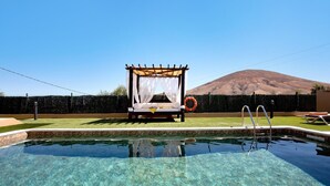 Una piscina nítida amb un pont de fusta, una tenda blanca i un bou salvavides.