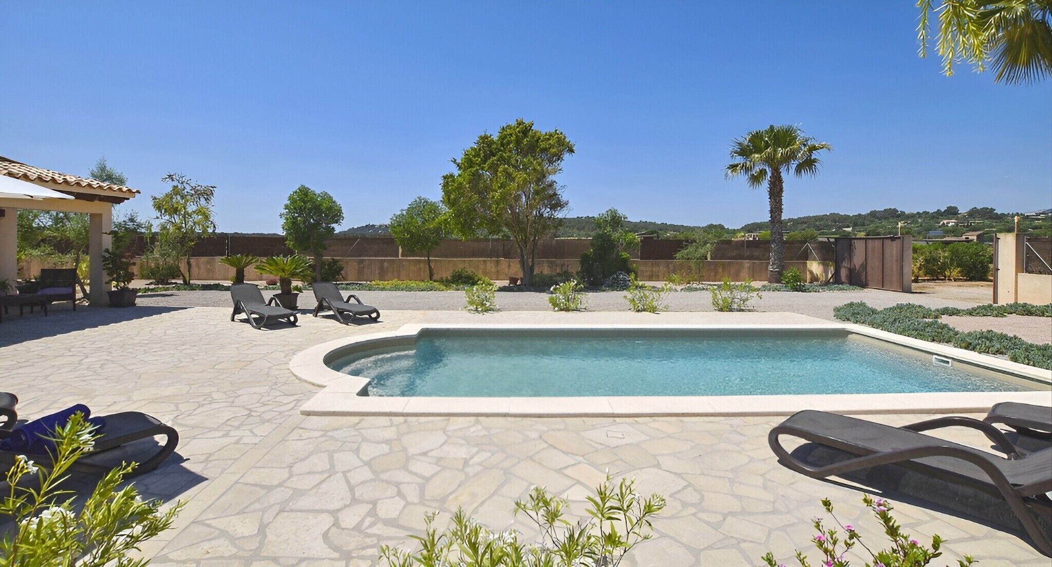 Una piscina con sillas de descanso, una pérgola y vistas a un paisaje montañoso.