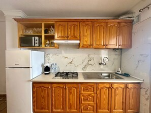 A kitchen with wooden cabinets, a white refrigerator, a gas stove, a microwave, and a sink.
