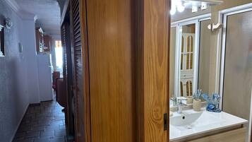 A hallway leading to a bathroom with a sink, mirror, and decorative items.
