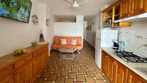 Eine Küche mit Holzausstattung, einem weißen Kühlschrank, einem Gasherd und einem Essbereich mit einer Couch.