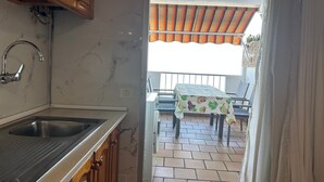 Eine Küche mit Spüle, Schränken und Blick auf eine Terrasse mit Tisch und Stühlen.