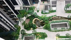 Eine Vogelperspektive eines modernen Gebäudes mit mehreren Etagen, mit einem zentralen Innenhof, der eine kleine Wasseranlage inmitten von Grünflächen und Sitzbereichen zeigt.