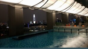 Ein Poolbereich mit Blick auf eine nächtliche Skyline.