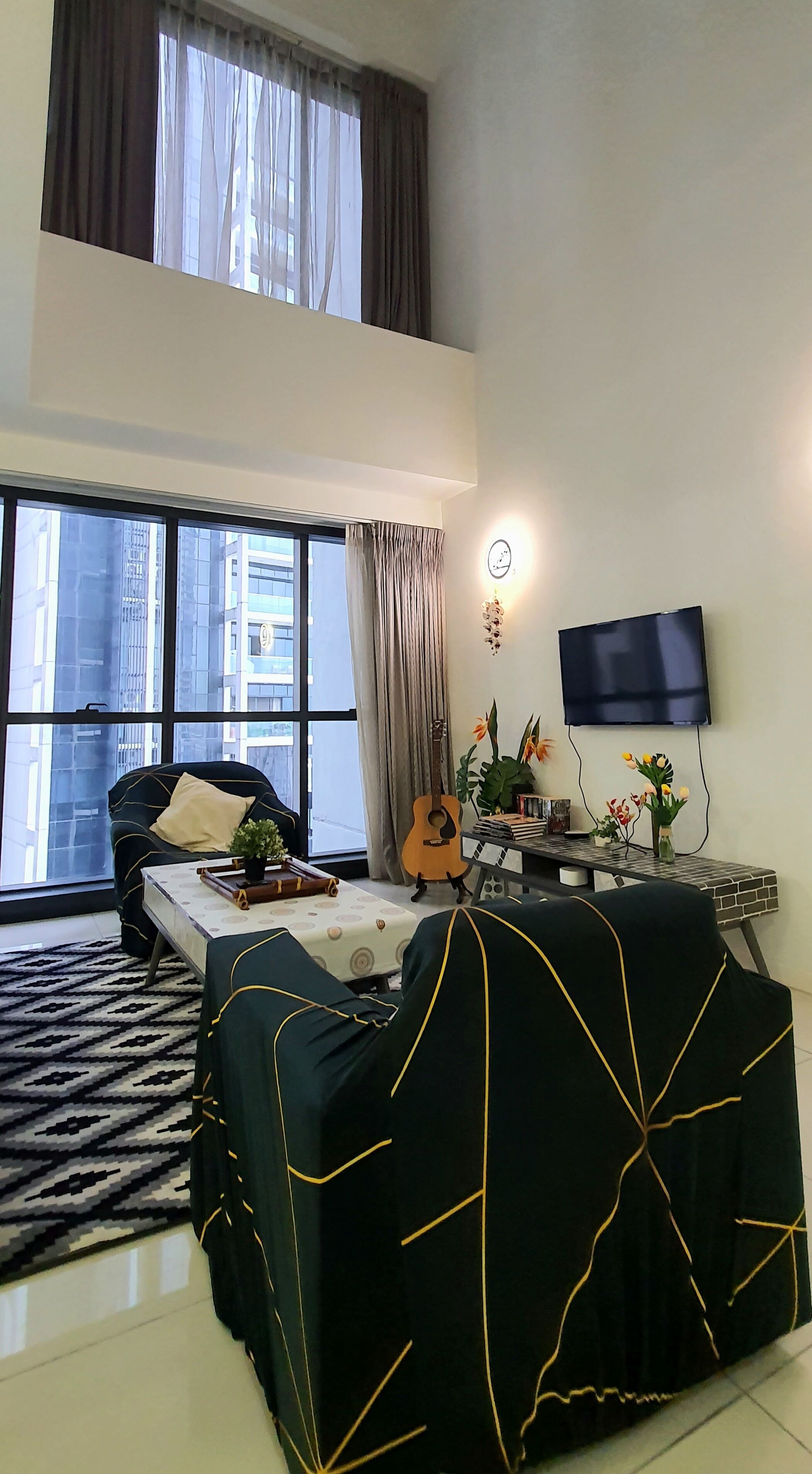 A modern living room with a sofa, a coffee table, a guitar, and a TV.