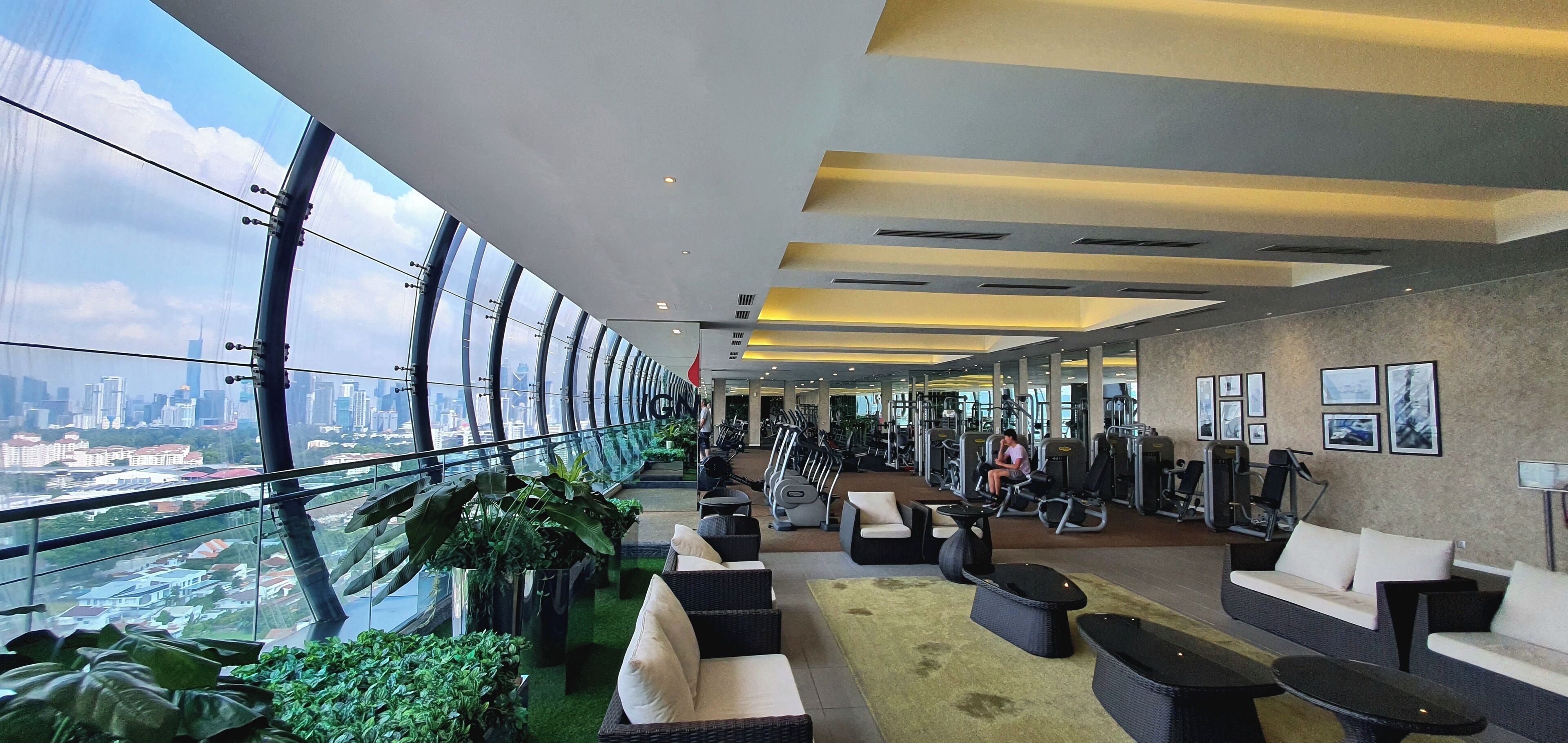 Un vaste espace intérieur comprenant une salle de sport, des sièges et une vue sur la ville.