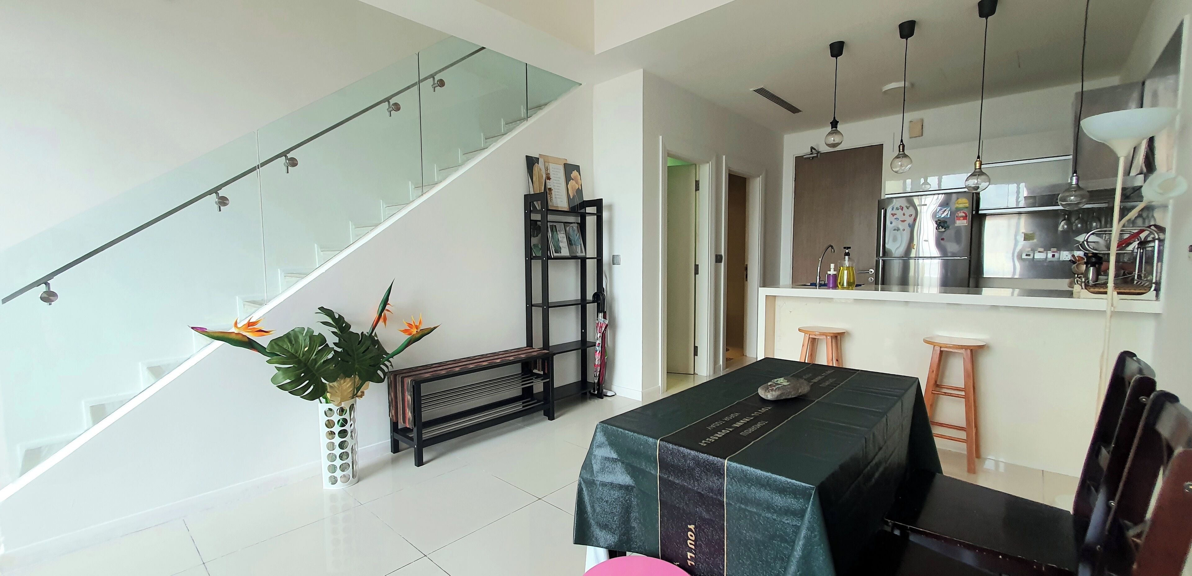 Eine moderne Küche mit Edelstahlgeräten, ein Essbereich mit Tisch und Stühlen sowie eine Treppe mit Glasgeländern.