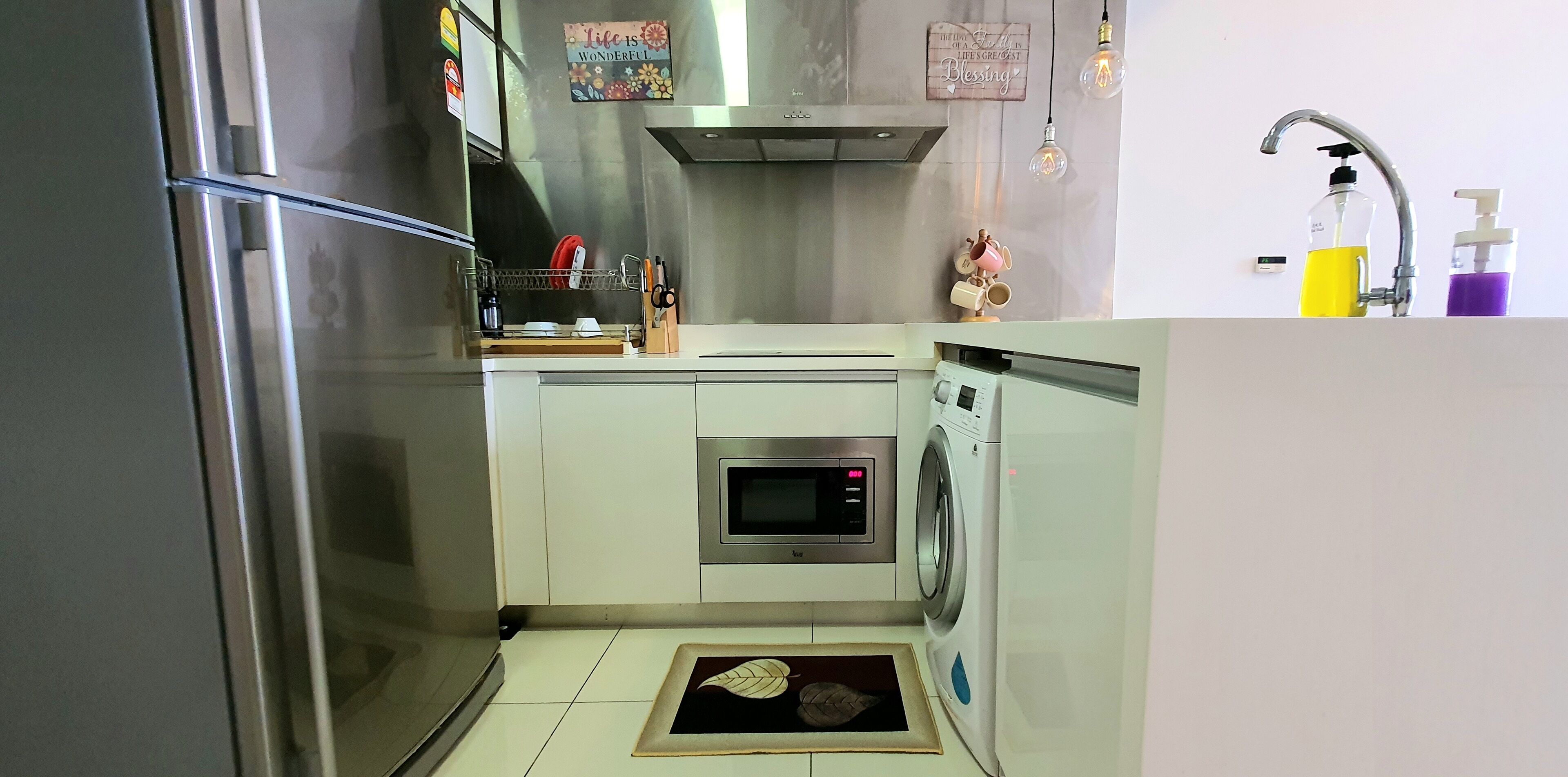 A compact kitchen with a built-in oven, microwave, and washing machine.