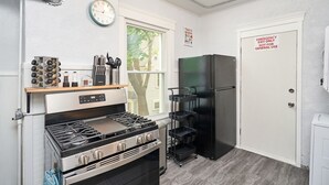 Uma cozinha compacta com fogão a gás, geladeira e um relógio na parede.