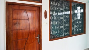 A wooden door with a metal handle and a glass door with a leaf pattern.