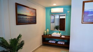 A bathroom with a sink, mirror, and a potted plant.