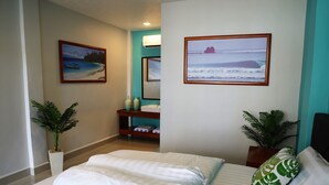 A hotel room with a bed, two potted plants, a nightstand, a mirror, and two framed pictures on the wall.