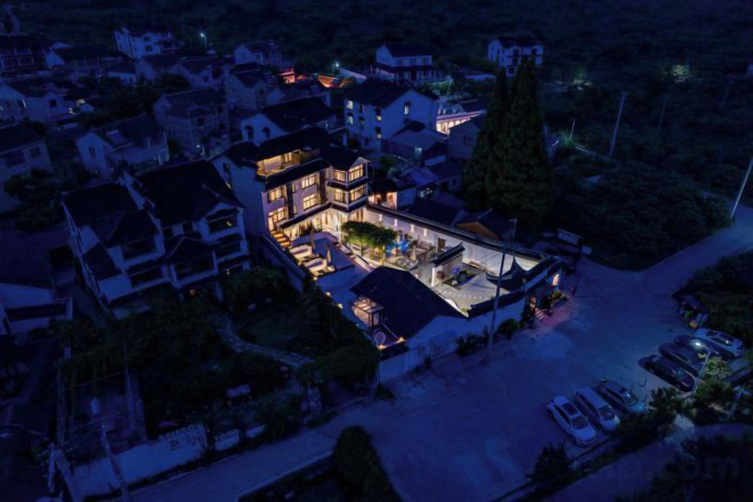 An aerial view of a large, multi-story building with a spacious outdoor area and multiple vehicles parked in front.