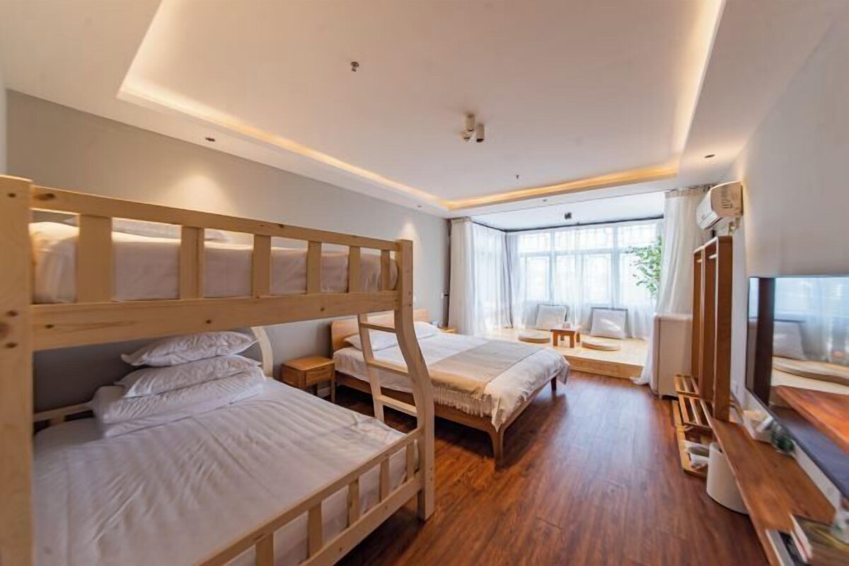 Une chambre avec des lits superposés, un bureau, une chaise et une fenêtre avec des rideaux.