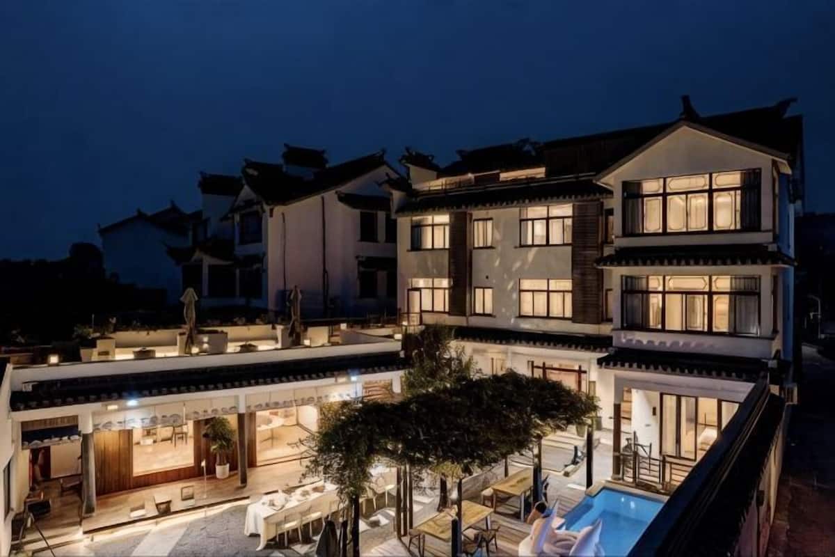 A multi-story building with a courtyard, outdoor seating, and a swimming pool.
