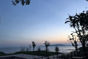 A coastal view with a wooden deck, trees, and a distant shoreline. - Suzhou Taihu Lakeside·Shanhu Yin·Holiday Homestay (Suzhou)