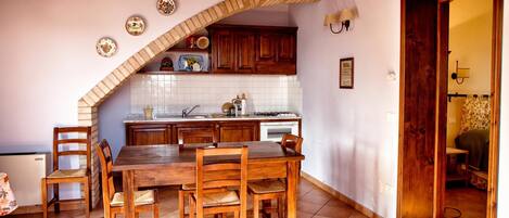 Una cocina con una mesa de comedor y sillas, armarios de madera, salpicadero de azulejos y techo de madera.
