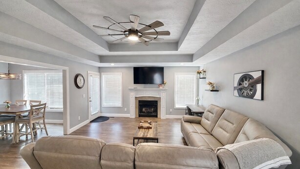 A spacious living room with a fireplace, a large sofa, and a dining area with a table and chairs. - Vette City retreat convenient to Mammoth Caves, Beech Bend, NCM, WKU. (Bowling Green)