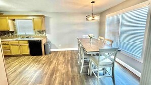 A kitchen with wooden cabinets, a dining table with chairs, and a pendant light. - Vette City retreat convenient to Mammoth Caves, Beech Bend, NCM, WKU. (Bowling Green)