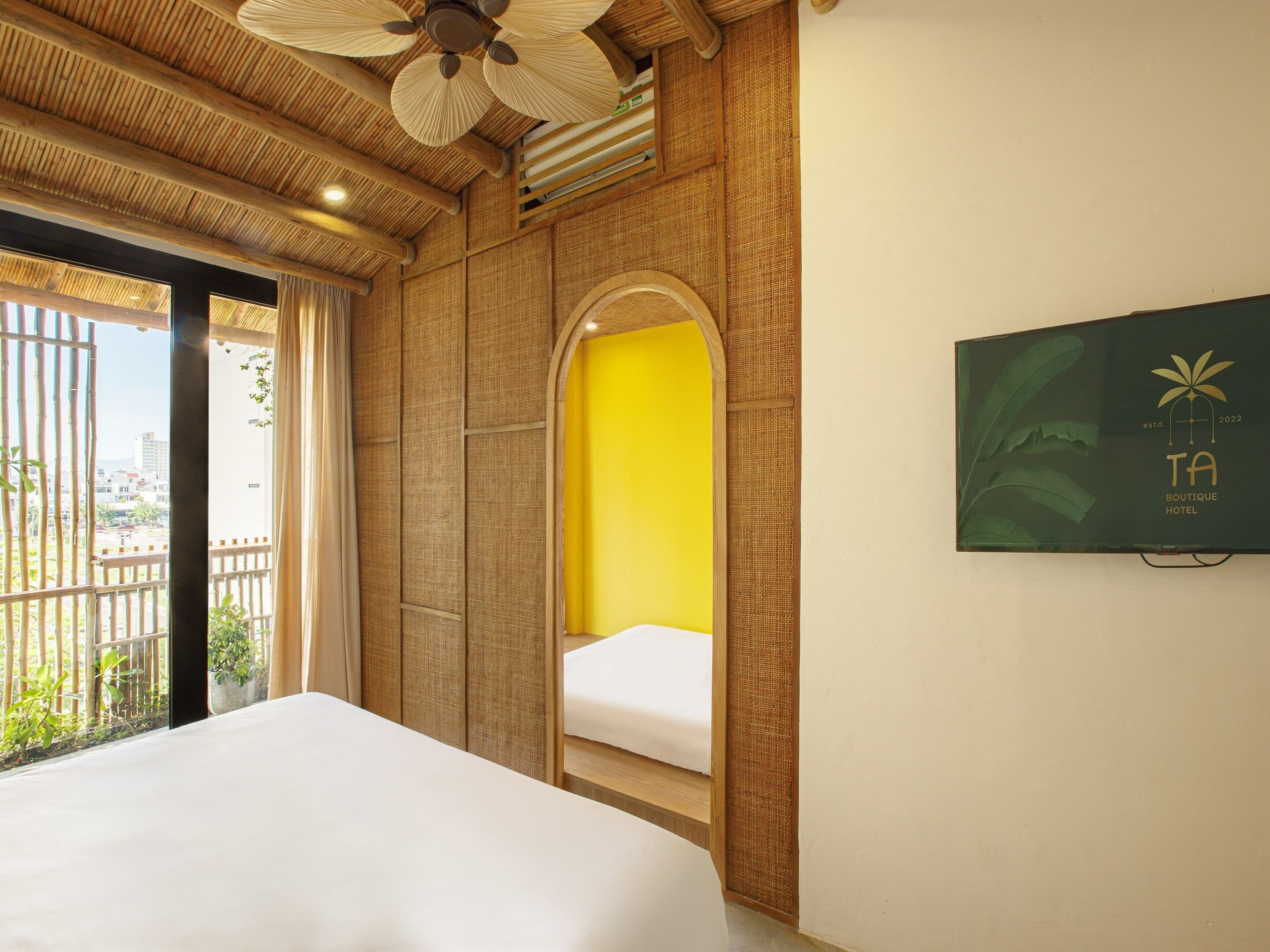 A hotel room with a bed, a large window, and a wall-mounted sign.