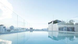 Een modern hotel met een zwembad op het dak en een helder uitzicht over de skyline van de stad.