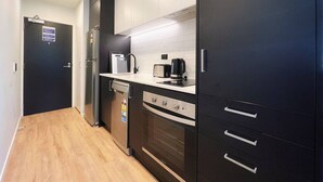 A modern kitchen with a dishwasher, oven, and a coffee maker on the countertop.