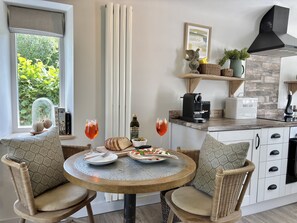 A dining area with wicker chairs, a round table, and a view of greenery outside. - Drovers Run - sleeps 2 guests  in 1 bedroom (Chard)