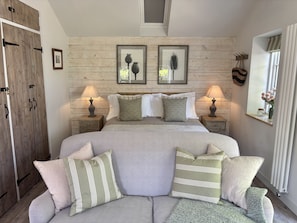 A bedroom with a bed, two bedside tables, a wooden wardrobe, and a window with curtains. - Drovers Run - sleeps 2 guests  in 1 bedroom (Chard)